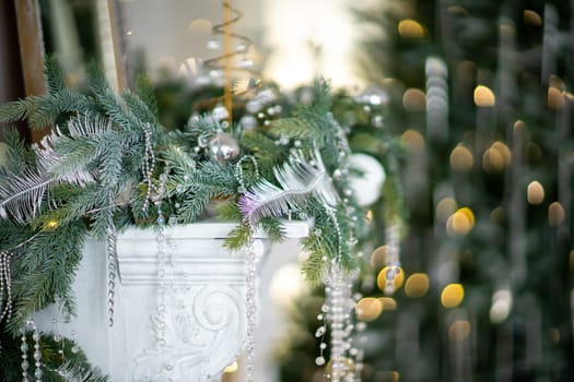 Close-up of a festively decorated outdoor Christmas tree with balls on a blurred sparkling fairy background. Defocused garland lights, bokeh effect.