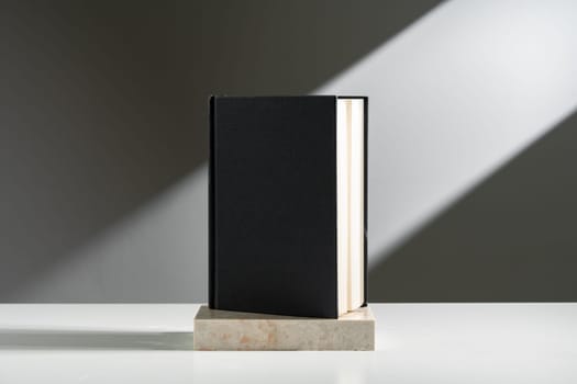 Black notepad in sunlight against gray background