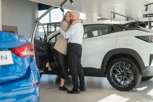 Mature Caucasian couple hugging with happiness while buying a new car.