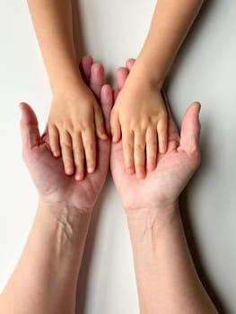 Mothers hands holding childs hands on white background.