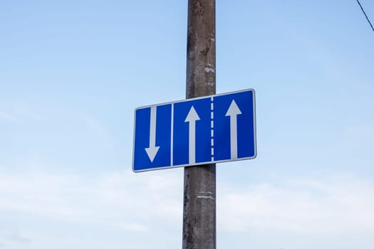 Road sign with arrows on blue sky background