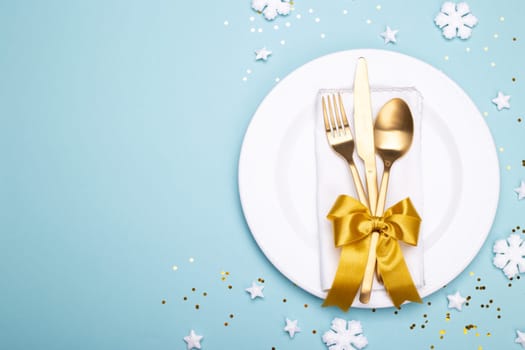 Christmas or new year table setting with golden cutlery on the blue background with copy space