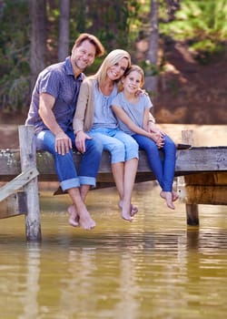 Portrait, lake and girl with family, smile and happiness with water or nature with vacation or getaway trip. Parents, hug or mother with father or child in a forest or holiday with boardwalk or relax