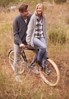 Couple, happy and field with retro bicycle on holiday, adventure or date with sustainable transport. Man, woman and vintage bike with smile for vacation with journey in nature, path or environment