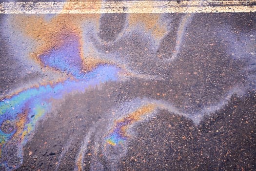 Oil spill on wet asphalt, parking lot with dividing line