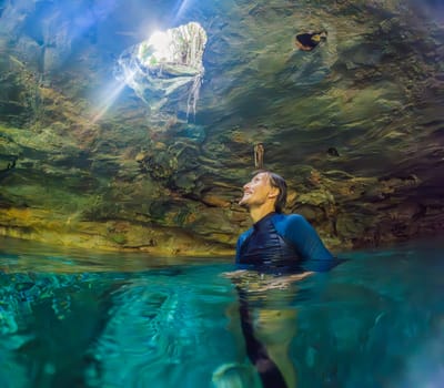 Man immersed in the enchanting beauty of a Mexican cenote, surrounded by crystal-clear waters and captivating natural formations