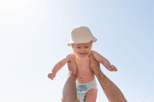 Father's playful lift of his baby under the sunny sky. Concept of nurturing and joy in baby's first year