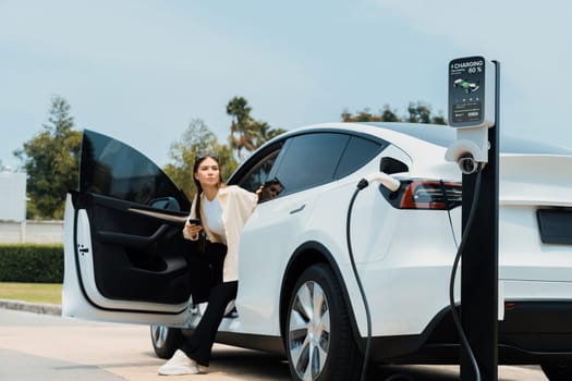 Young woman use smartphone to pay for electricity for EV car. Expedient