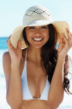 Woman, hat and smile at beach in portrait, nature and traveling to ocean for peace on vacation. Female person, outdoors and calming water on summer holiday, getaway and relaxing on tropical island