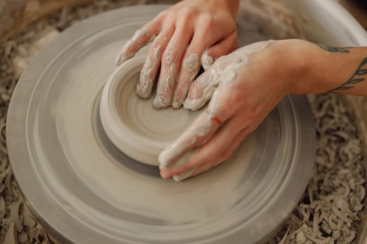 Close up of artisan's hands shaping clay bowl in pottery studio. Pottery art and creativity