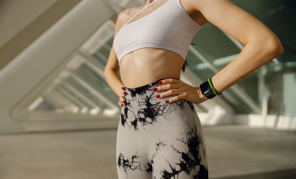 Close up of woman in sportswear have a rest after workout outside standing on building background