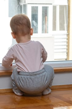 Toddler wants outside fun, looks through window. Concept of dreaming about playing outside