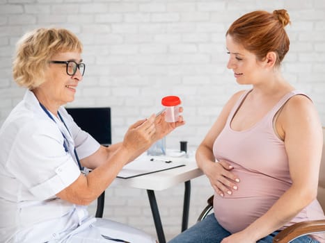 The doctor explains to a pregnant patient how to pass a urine test.