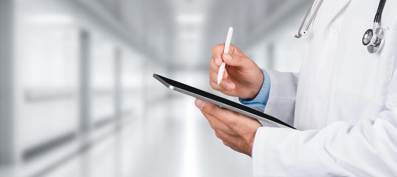 A close-up of a doctor's hands using a stylus on a digital tablet