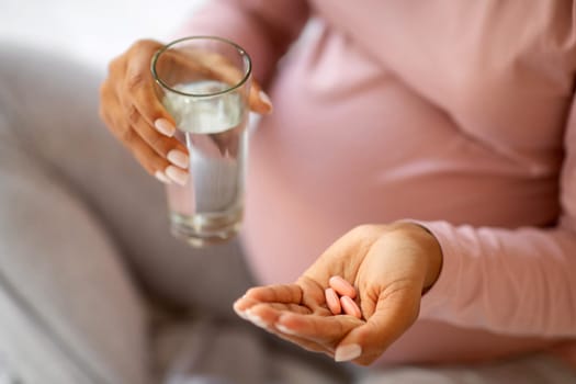 Prenatal Vitamins And Supplements. Unrecognizable black pregnant woman taking pills at home