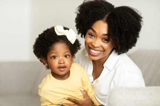 Motherhood. Portrait of happy cute african american young beautiful mother and little daughter toddler bonding at home, enjoying time together. Black mom cuddling with her sweet child girl