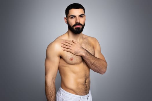 Sexy topless middle eastern young man posing shirtless on grey