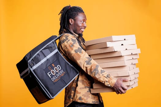 Deliveryman carrying stack of pizza boxe