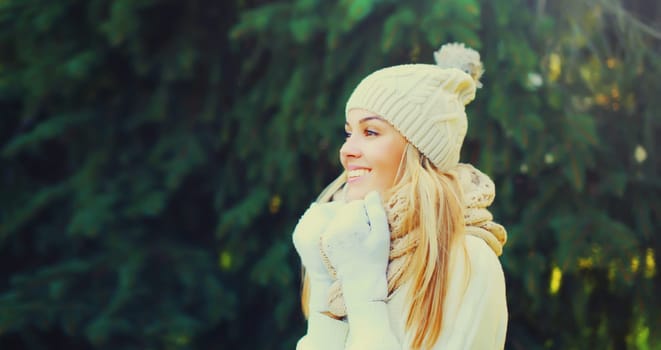 Winter portrait of happy smiling young woman in hat, scarf in forest on christmas tree background