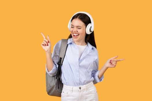 Happy lady student dancing to music with headphones