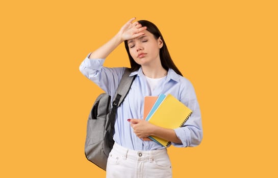 Exhausted student with copybooks and backpack over yellow background