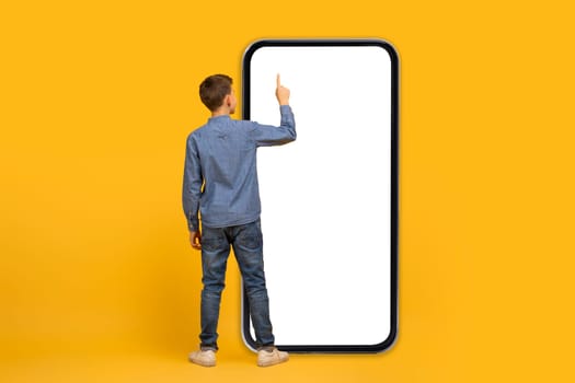 Teenage boy standing and pointing at huge smartphone screen with white display