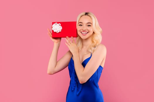 Happy blonde woman with gift box, joyful surprise gesture