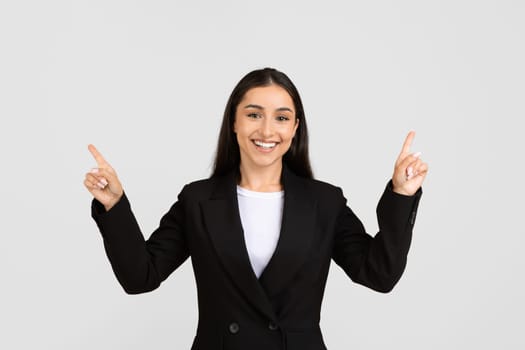 Joyful european businesswoman pointing upwards with both hands