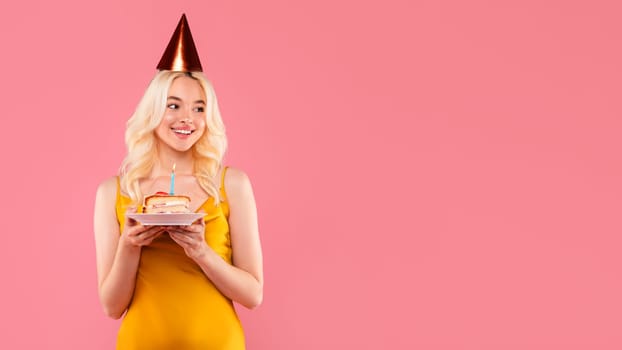 Happy young woman with cake and candle in party attire