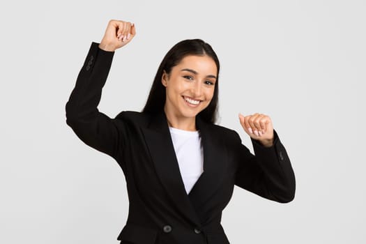 Joyful european businesswoman celebrating success with raised arms