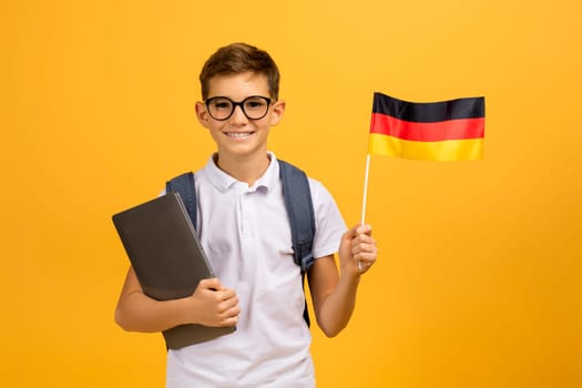 Portrait Of Happy Teen Boy With Backpack Holding German Flag And Laptop