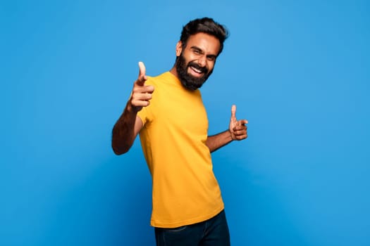 Excited indian man in yellow pointing with both hands to camera