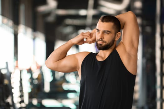 Portrait Of Athletic Young Man Stretching Arm Muscles At Gym