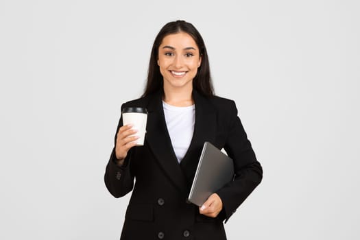 Smiling young businesswoman with coffee and laptop