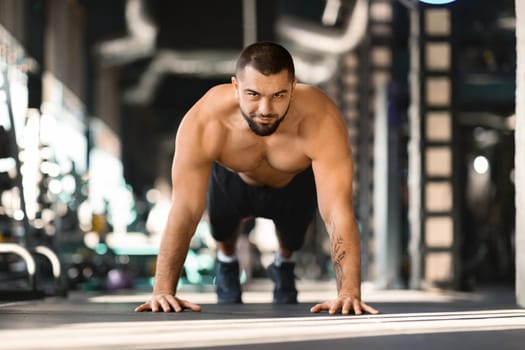 Sporty Young Male Making Straight Arm Plank Exercise While Training At Gym