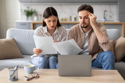 Anxious couple with laptop and papers on the couch