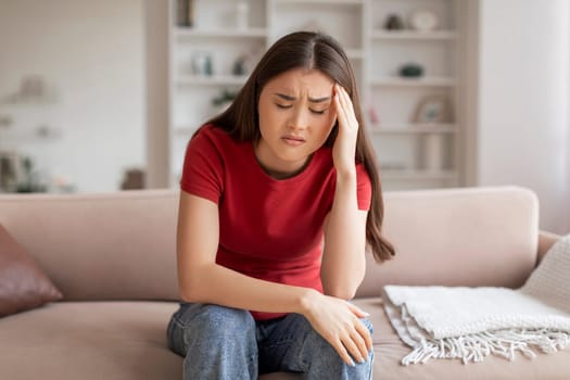 Anxious young asian woman suffering signs of headache or stress