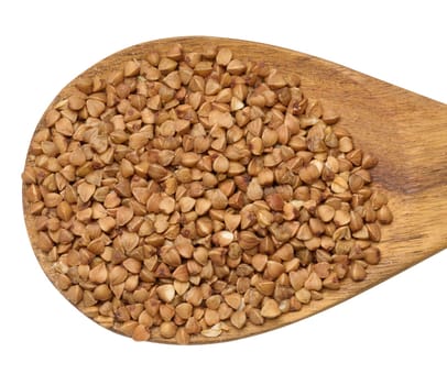 Raw buckwheat kernels in a wooden spoon on an isolated background