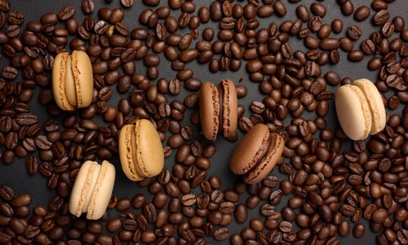 Multi-colored macarons on a background of coffee beans, top view