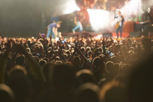 Crowd, live concert and stage with dancing audience as music festival for entertainment, performance or carnival. People, hands and fans of musicians with lighting for rock event, rave or vacation