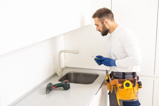 plumber installs kitchen faucet. refurbishment in the apartment.