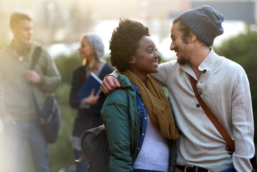 Students, university and conversation of interracial couple of friends on campus with hug and an embrace outdoor. College, school education and diversity with a happy smile ready for class together