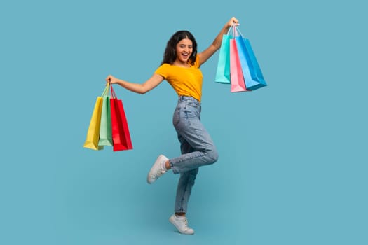 Excited young indian woman customer dancing with shopping bags