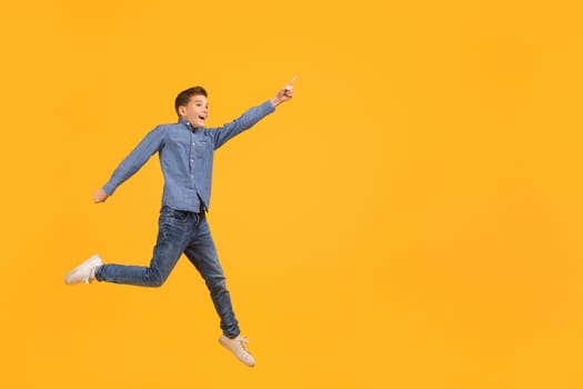 Look At This. Teen boy pointing aside while jumping up in air