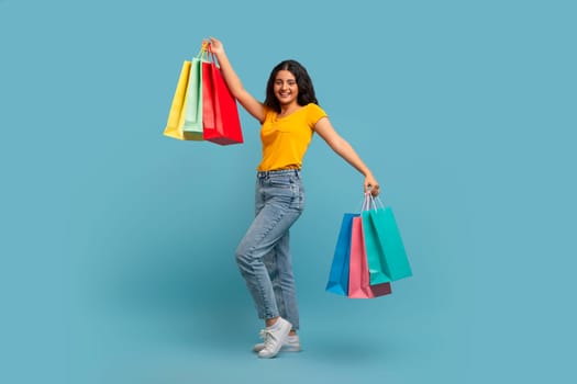 Overjoyed young indian woman consumer holding many colorful bags