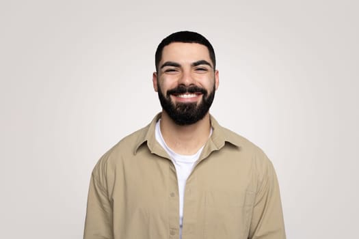Smiling handsome young latin guy with a beard in casual looking at camera