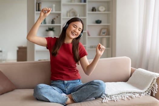Domestic Fun. Cheerful Young Asian Woman Listening Music In Wireless Headphones