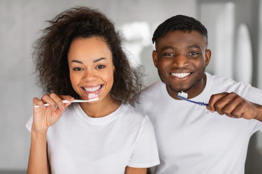 Portrait of happy married black couple brushing teeth in bathroom