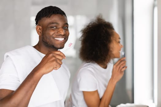 Happy black couple engages in oral care brushing teeth indoors