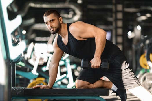 Motivated Male Athlete Training With Dumbbell At Modern Gym Interior